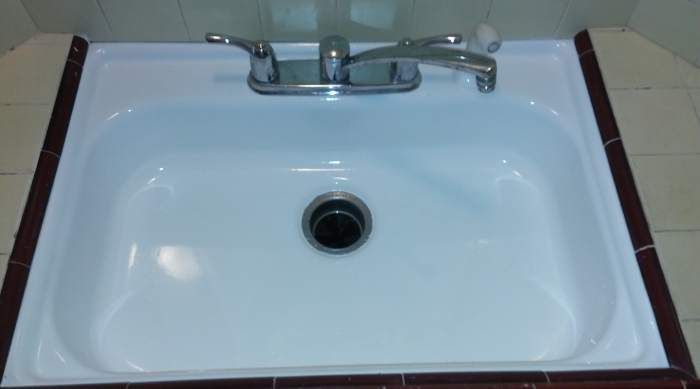 a white sink with a chrome faucet and drain in a bathroom .