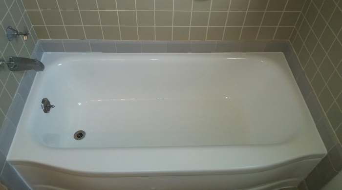 a white bathtub is sitting in a bathroom next to a tiled wall .