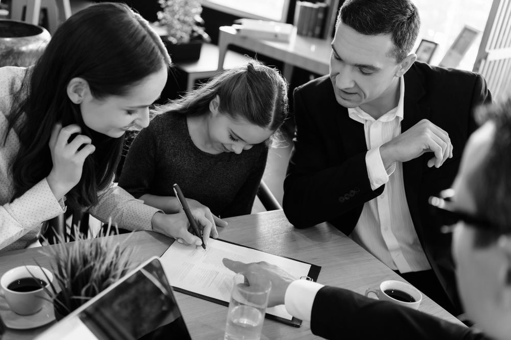 People collaborating around a table, one person writing on paper while others look on. - ev law in Bundall, QLD