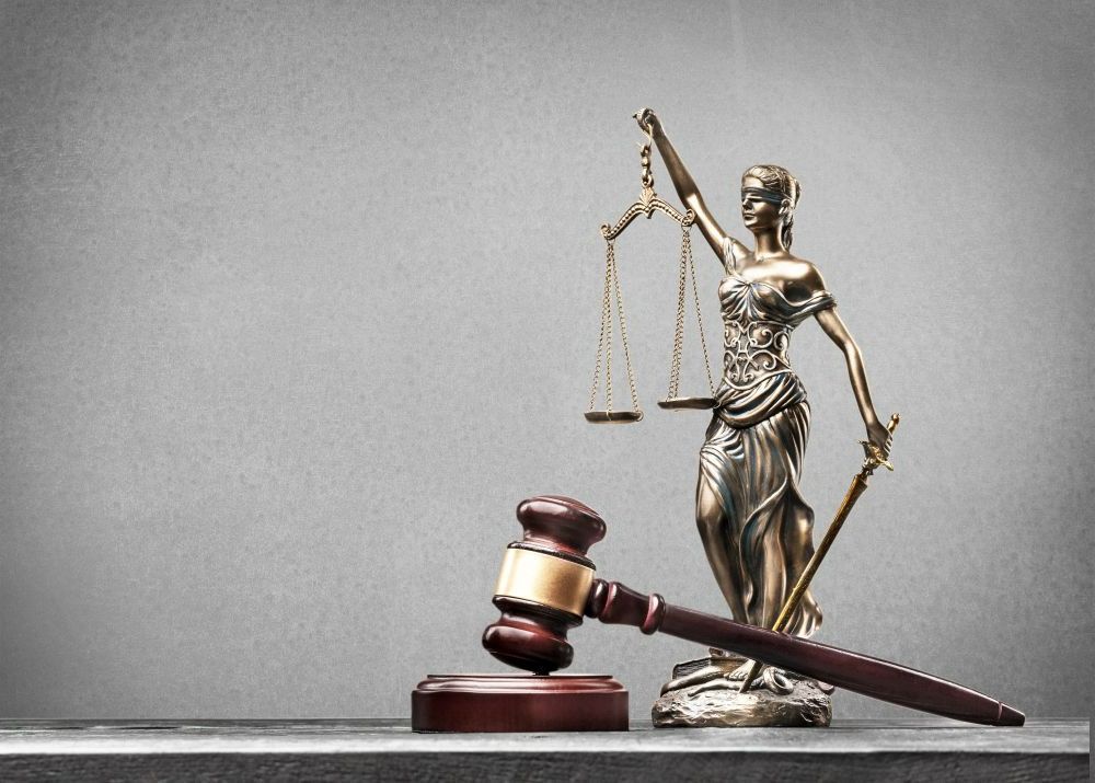 A Statue Of Justice Is Sitting Next To A Wooden Gavel — EV Law In Bundall, QLD