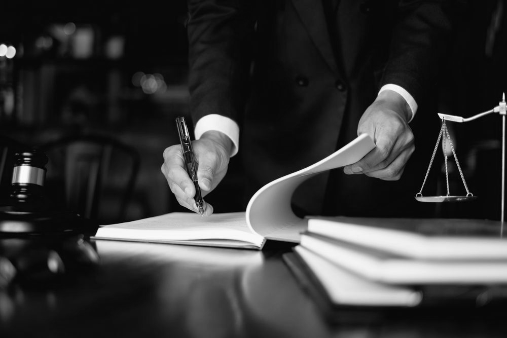 Lawyer signing documents at a desk with a gavel and scales of justice nearby - ev law in Bundall, QLD