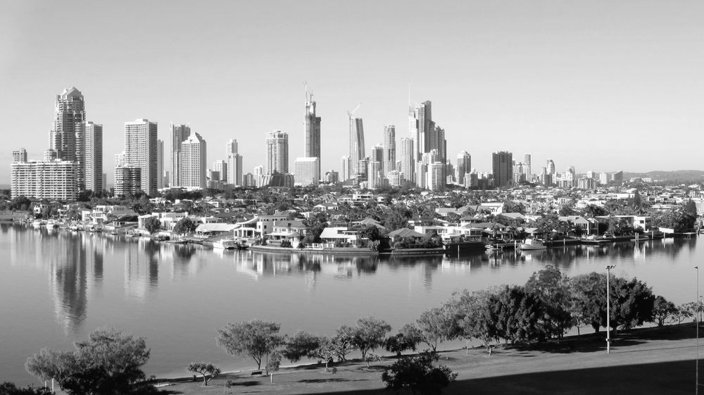 Skyline of modern high-rises across a calm river with their reflections under a clear blue sky. - ev law in Bundall, QLD