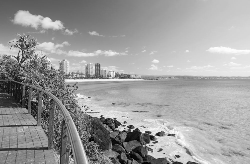 Coastal boardwalk overlooking turquoise ocean, rocky shore, and distant city skyline under a blue sky - ev law in Bundall, QLD