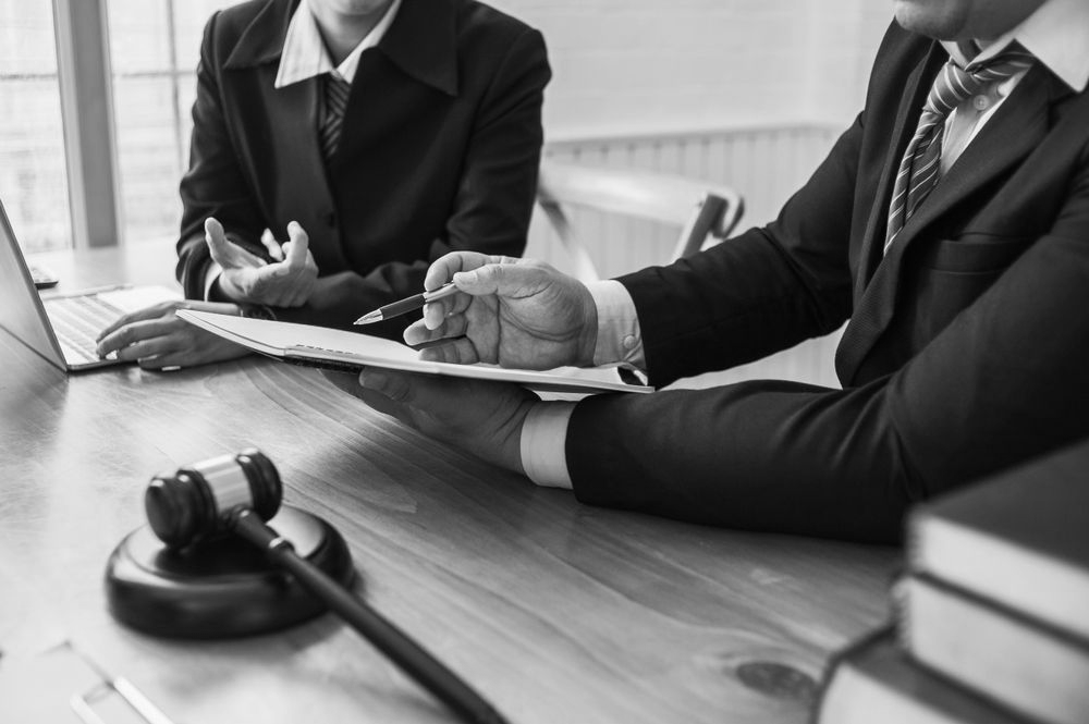 Two professionals reviewing documents at a conference table with a gavel in the foreground - ev law in Bundall, QLD