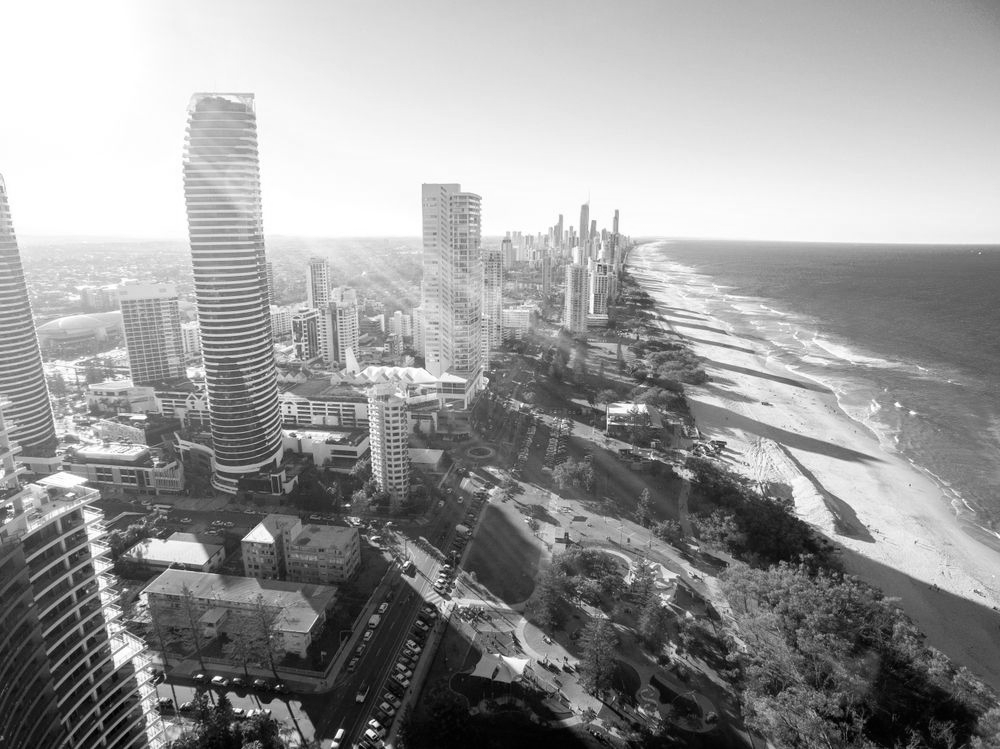 Aerial view of a coastal city with high-rise buildings, a sandy beach, and turquoise ocean. - ev law in Bundall, QLD