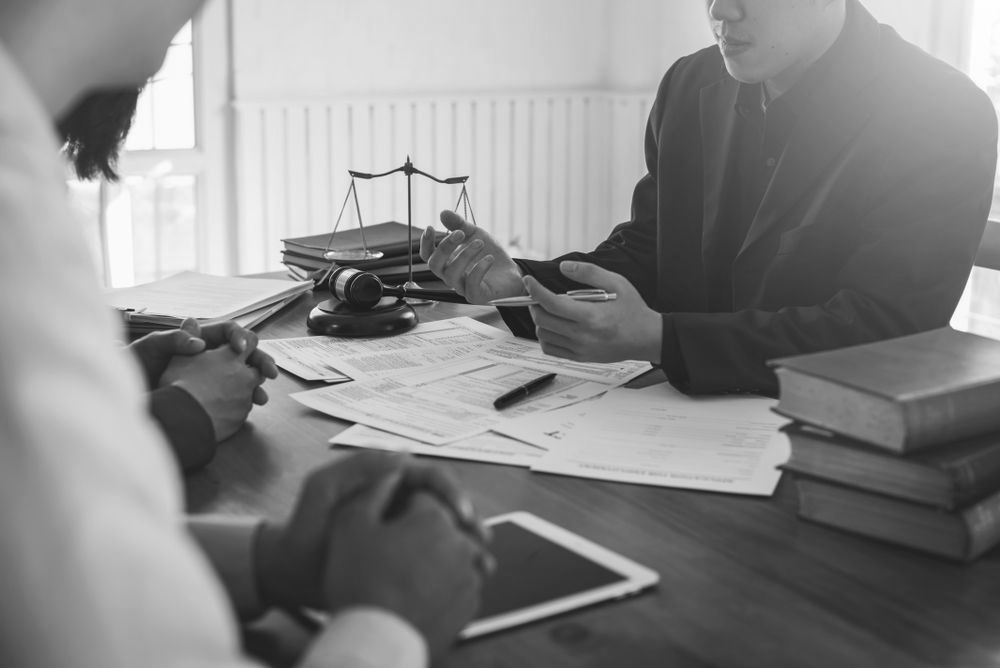 People in a meeting reviewing documents and a tablet beside a balance scale on a table - ev law in Bundall, QLD