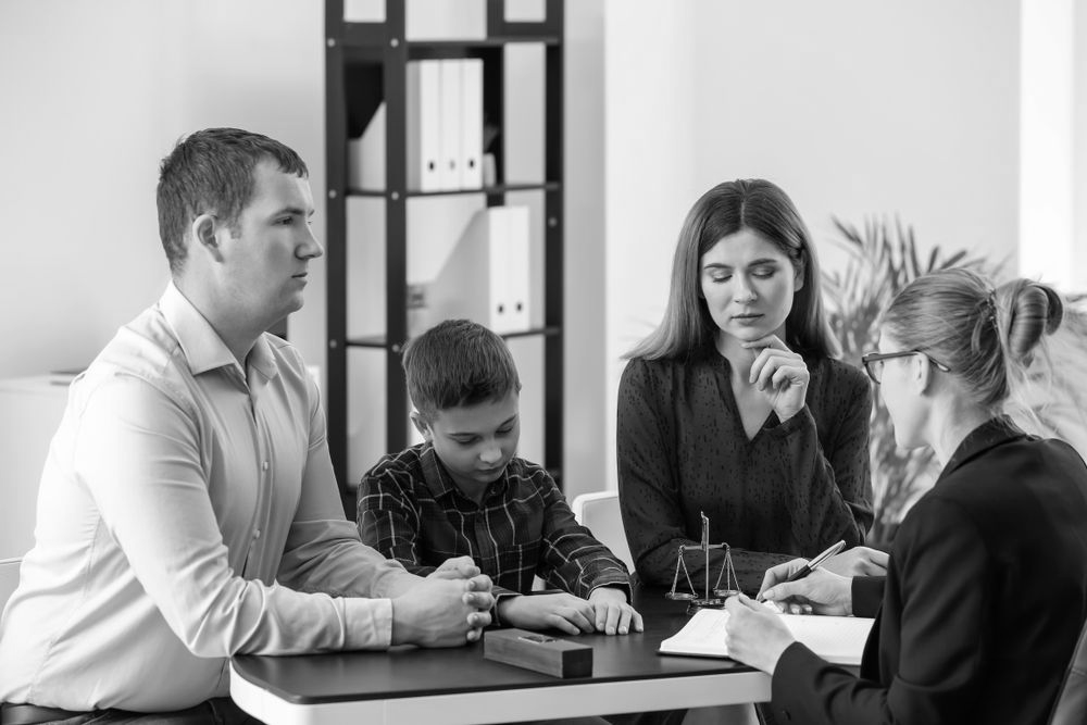 Four people discussing papers around a table in a meeting room - ev law in Bundall, QLD