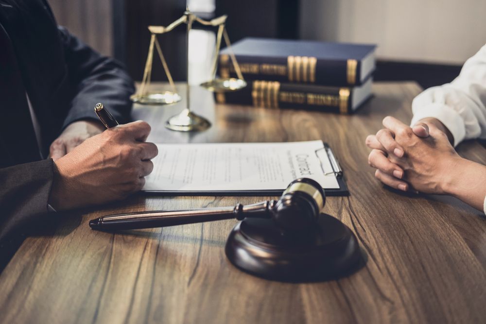 A Lawyer and It's Client Are Sitting at a Table With a Judge 's Gavel — EV Law In Bundall, QLD