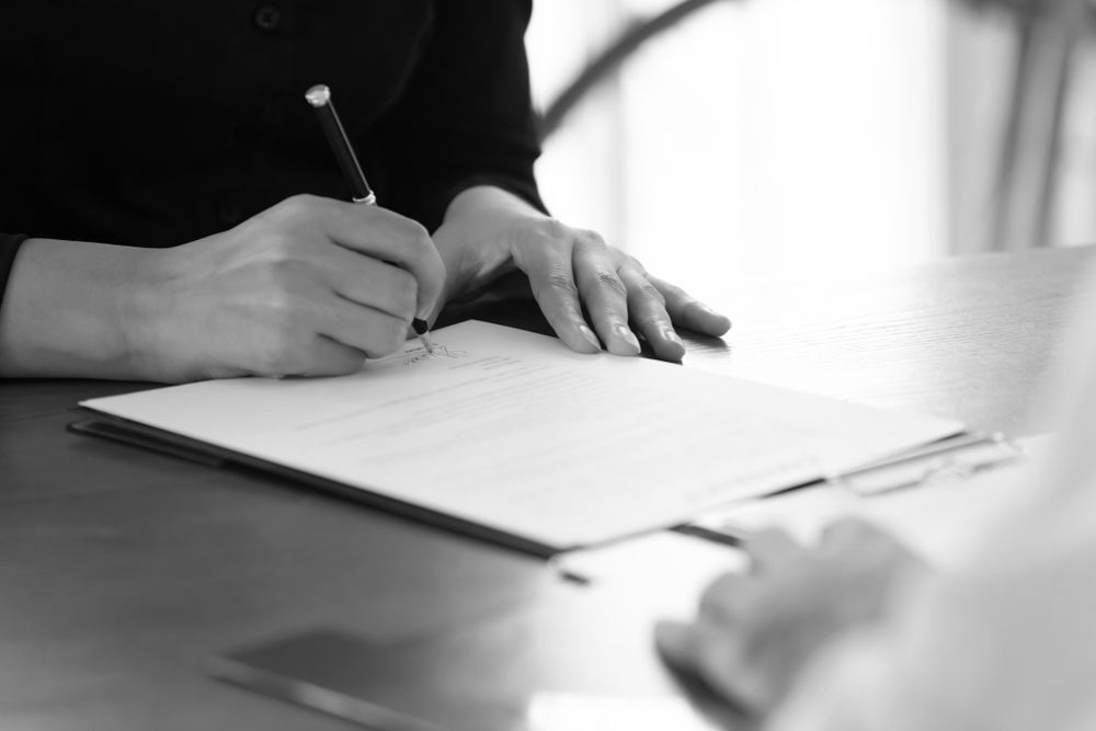 Hands writing on a document during a meeting at a table - ev law in Bundall, QLD