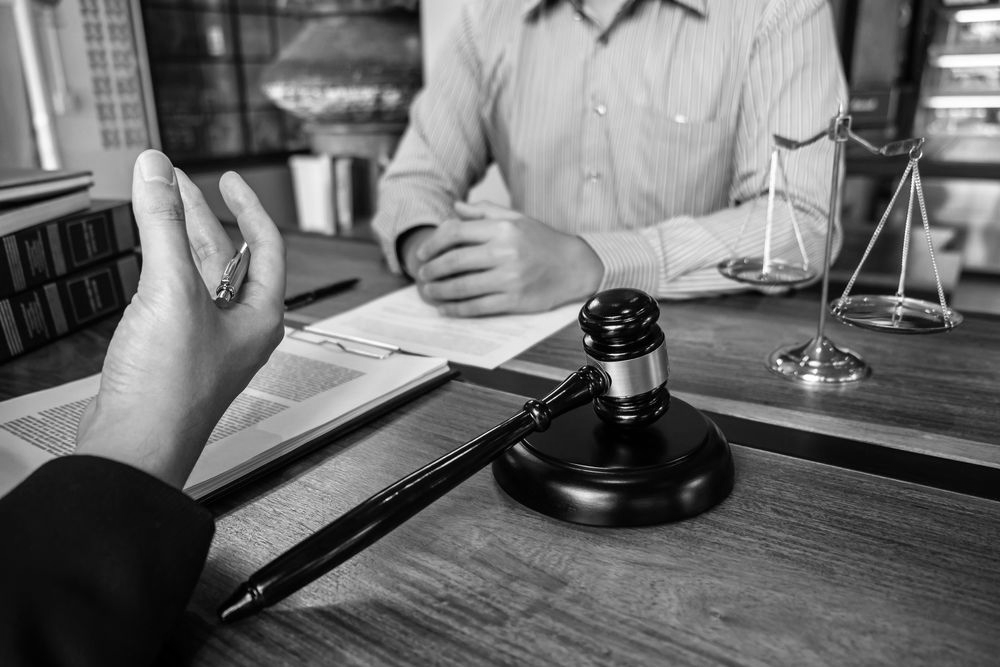 Handshake across a desk during a legal meeting, with a gavel and scales of justice visible. - ev law in Bundall, QLD