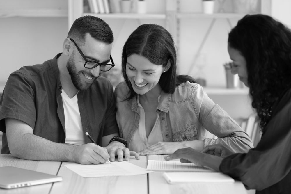 Three coworkers reviewing documents and smiling at a desk in a bright office - ev law in Bundall, QLD