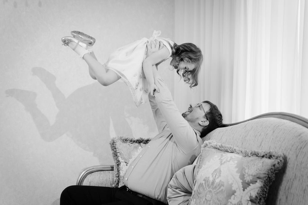 Couple laughing on a couch as one lifts the other playfully in a bright room - ev law in Bundall, QLD
