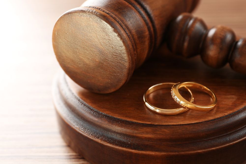 Two Wedding Rings Are Sitting on Top of a Wooden Gavel — EV Law In Bundall, QLD