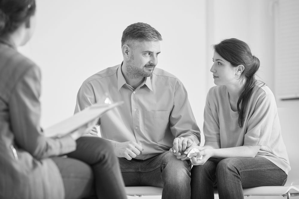 Three people in a counseling session, seated in a circle and talking attentively - ev law in Bundall, QLD
