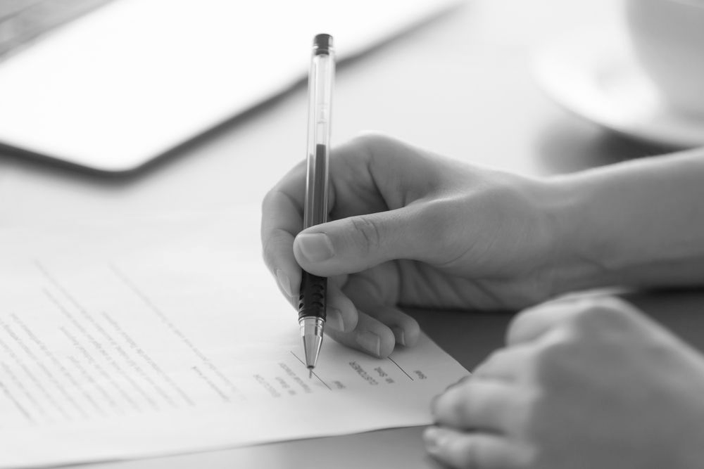 Hand writing on a form with a pen at a desk - ev law in Bundall, QLD