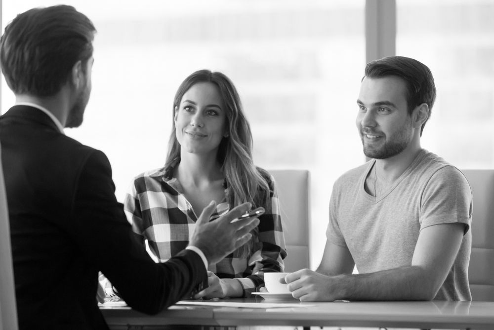 Three people in a bright office meeting, one speaking while two listen across a table. - ev law in Bundall, QLD