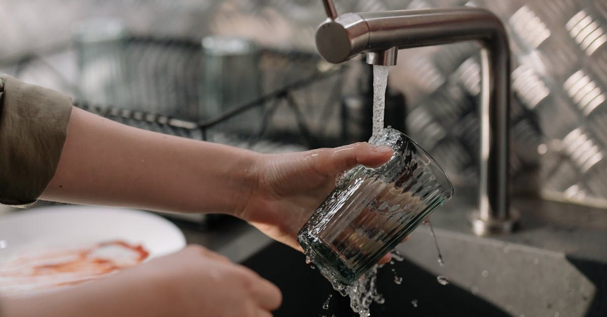 A person is washing a glass in a kitchen sink.