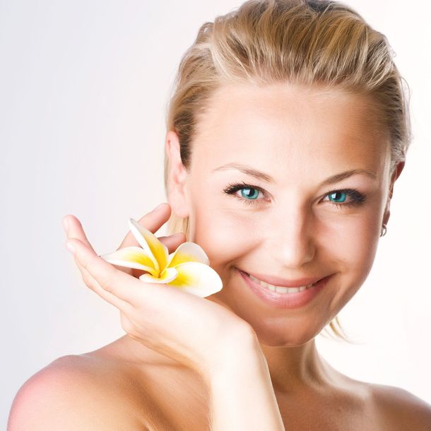 Eine Frau lächelt und hält eine Blume in der Hand