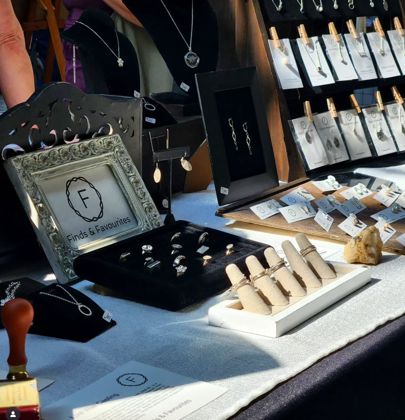 Jewelry display at a craft fair: necklaces, rings, and earrings on a table with a white tablecloth.
