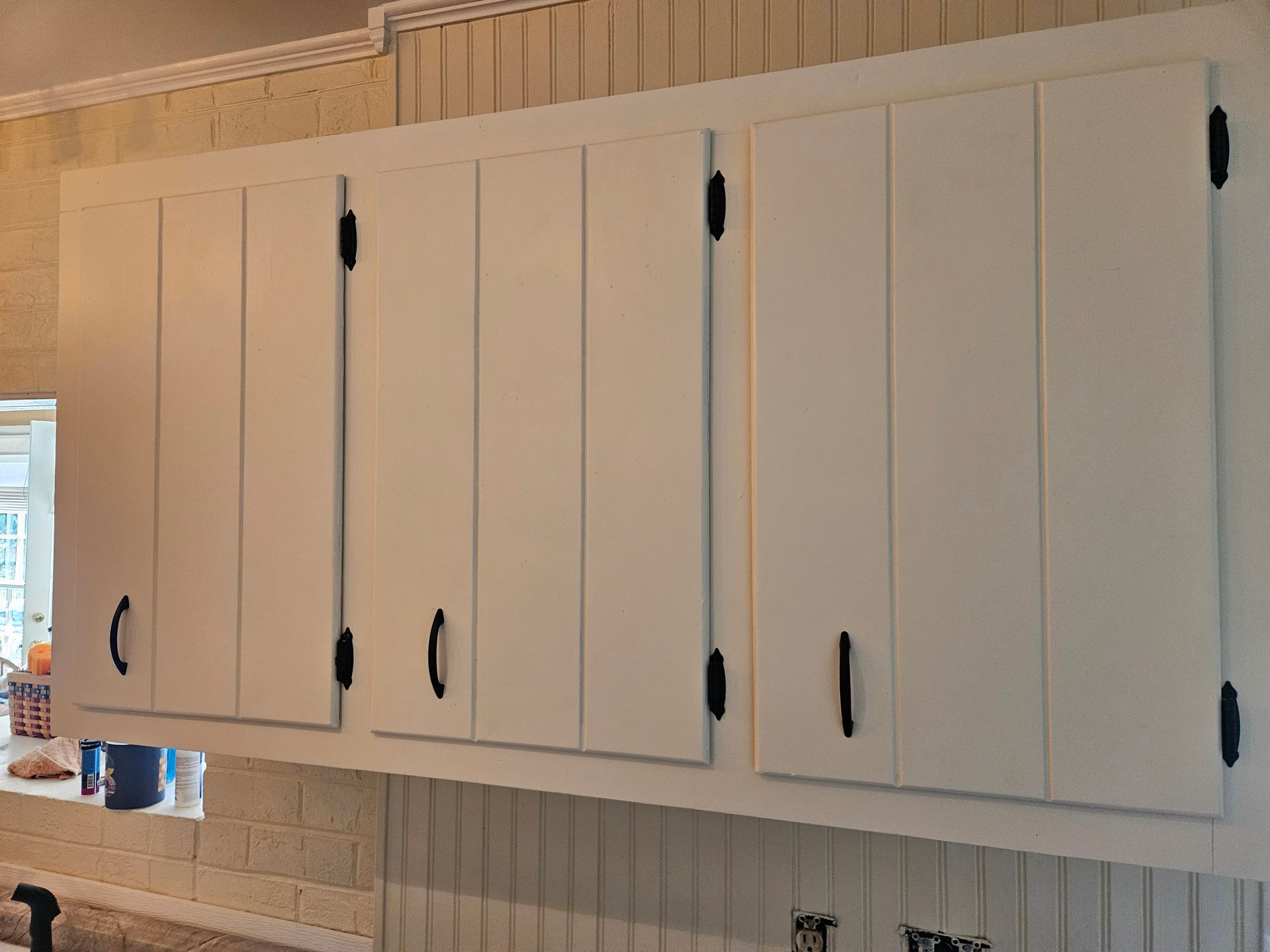 White kitchen with island, stainless steel appliances, and wood flooring.
