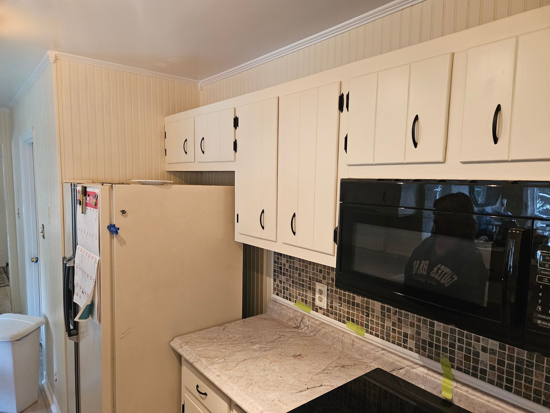 Modern kitchen with a large island, stainless steel appliances, light gray cabinets, and wooden accents.