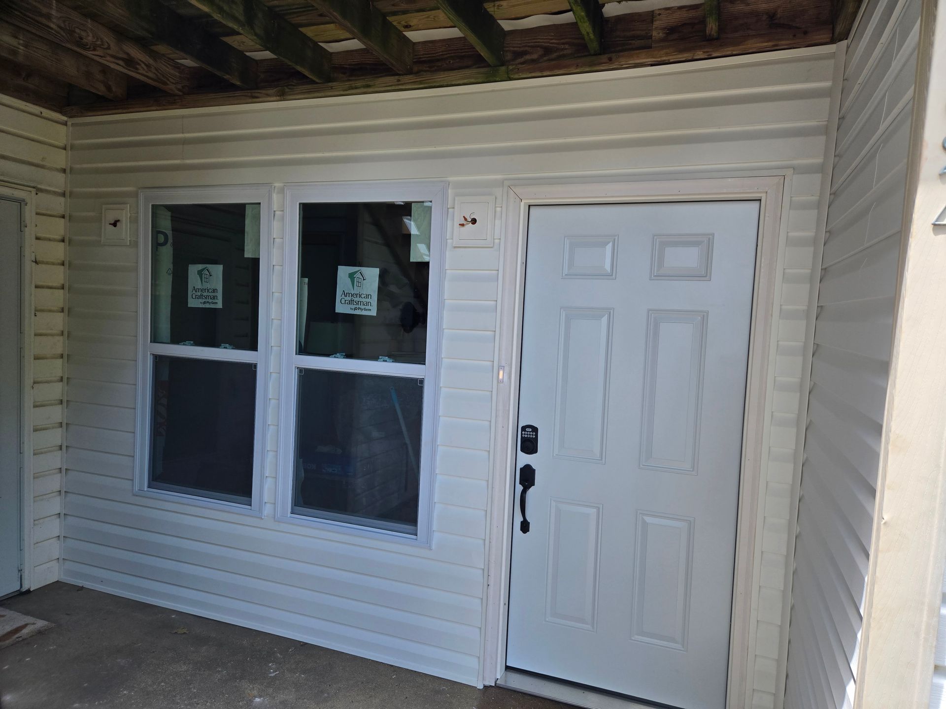 Construction worker in white hard hat and overalls inspects a window frame.
