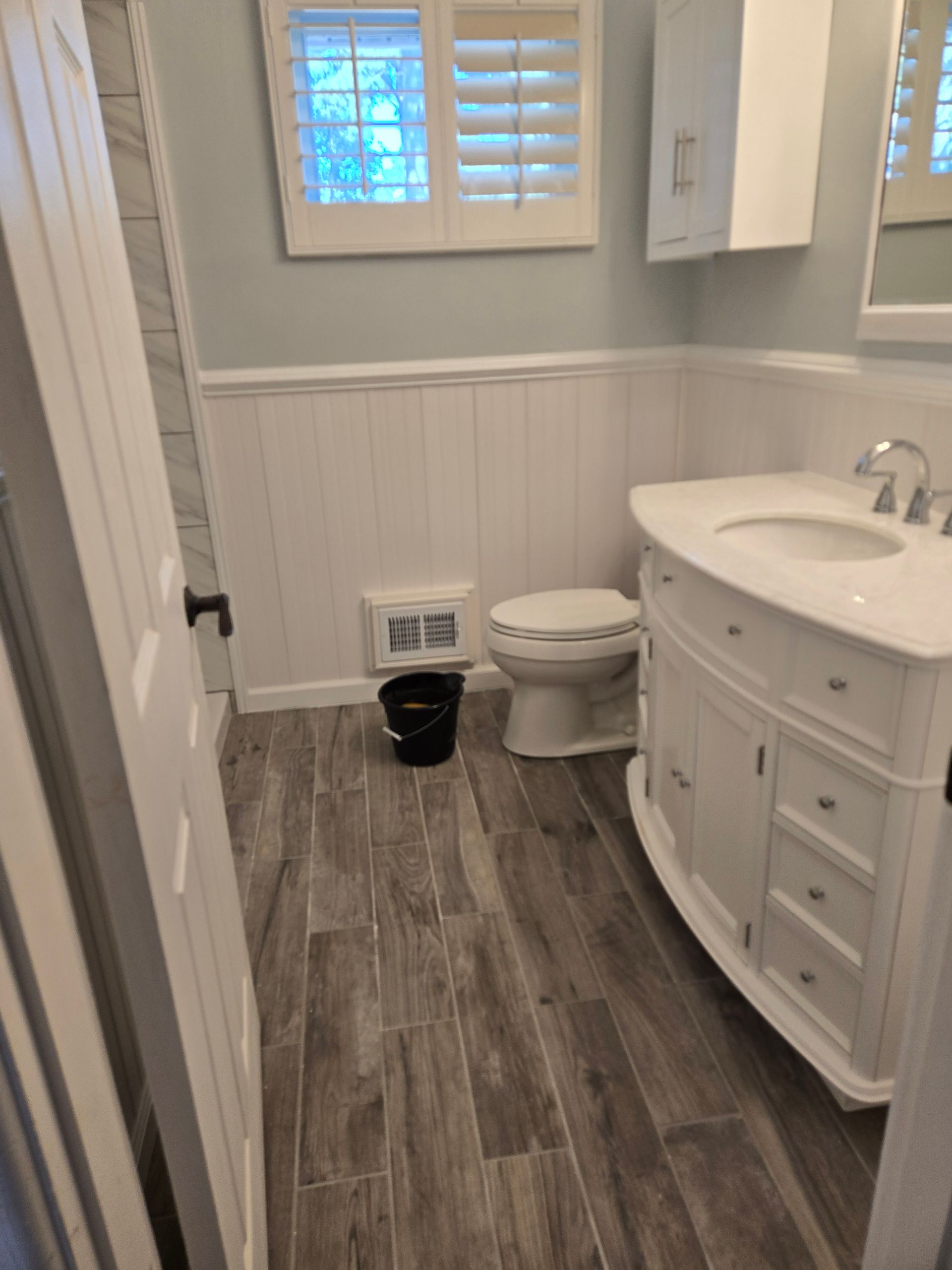 Kitchen under construction, with wood framing and completed white cabinets, granite countertops, and island.