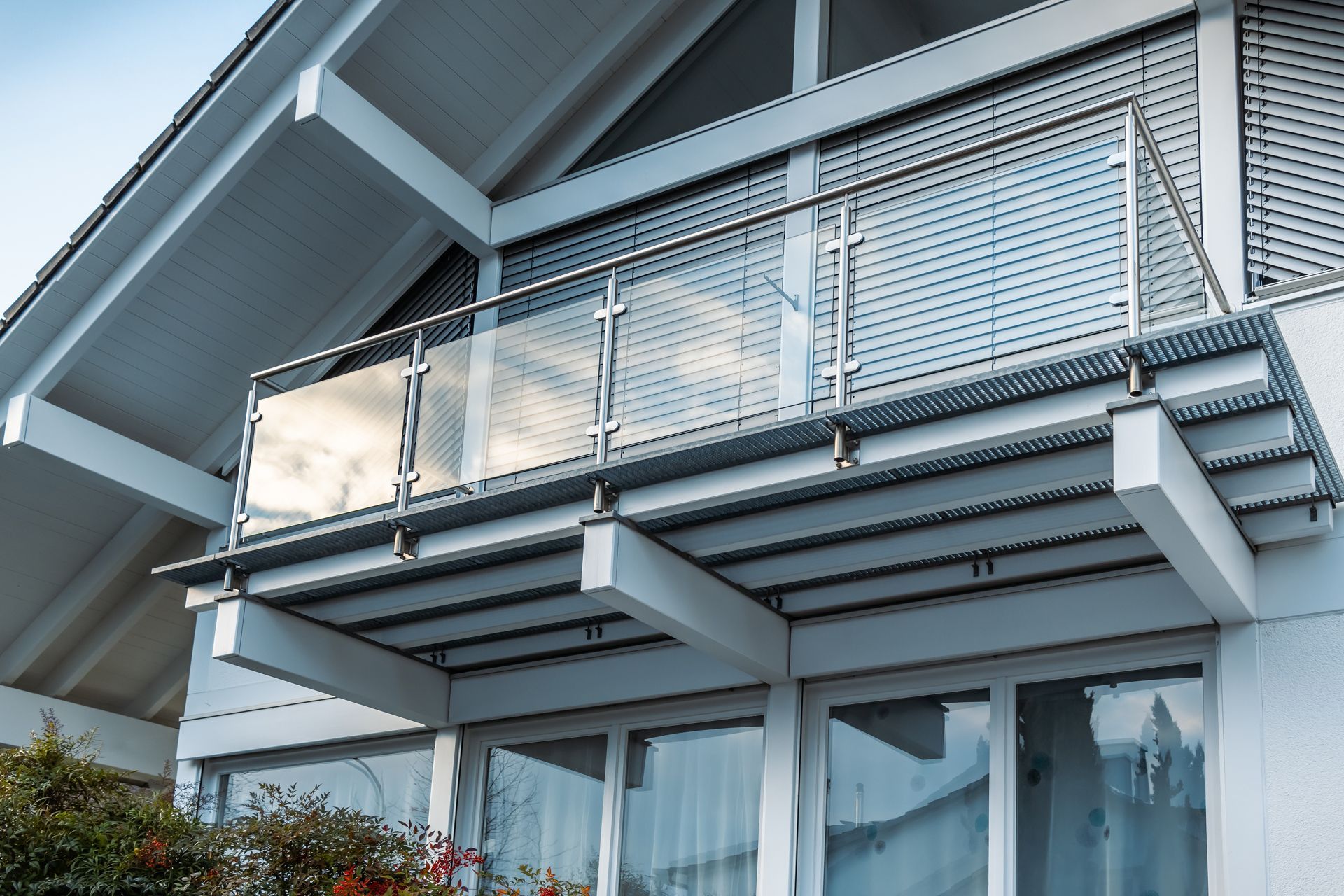 Balcony with metal and glass railing attached to a white building.