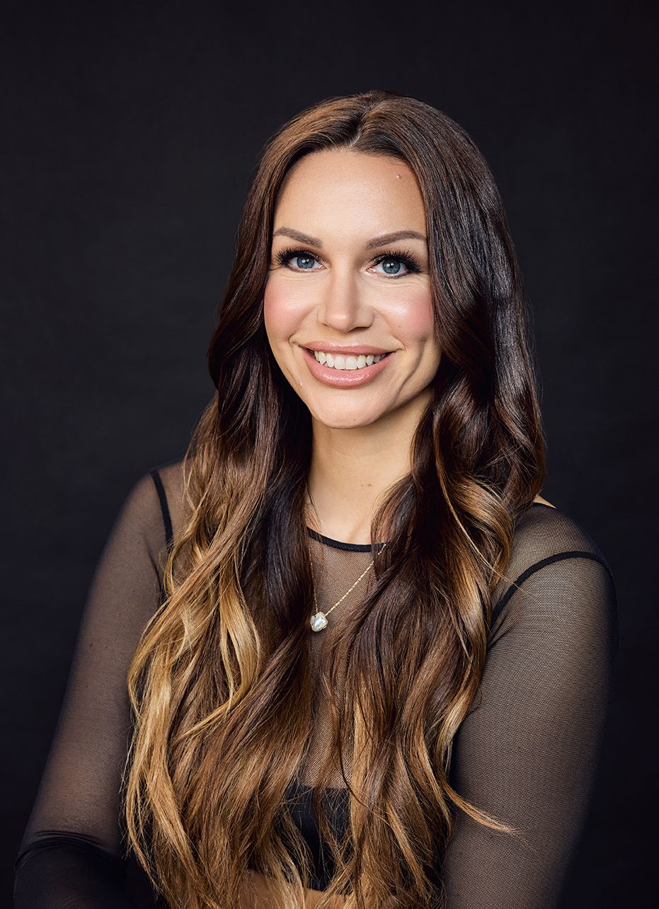 Eine Frau mit langen Haaren und einer Halskette lächelt in die Kamera.