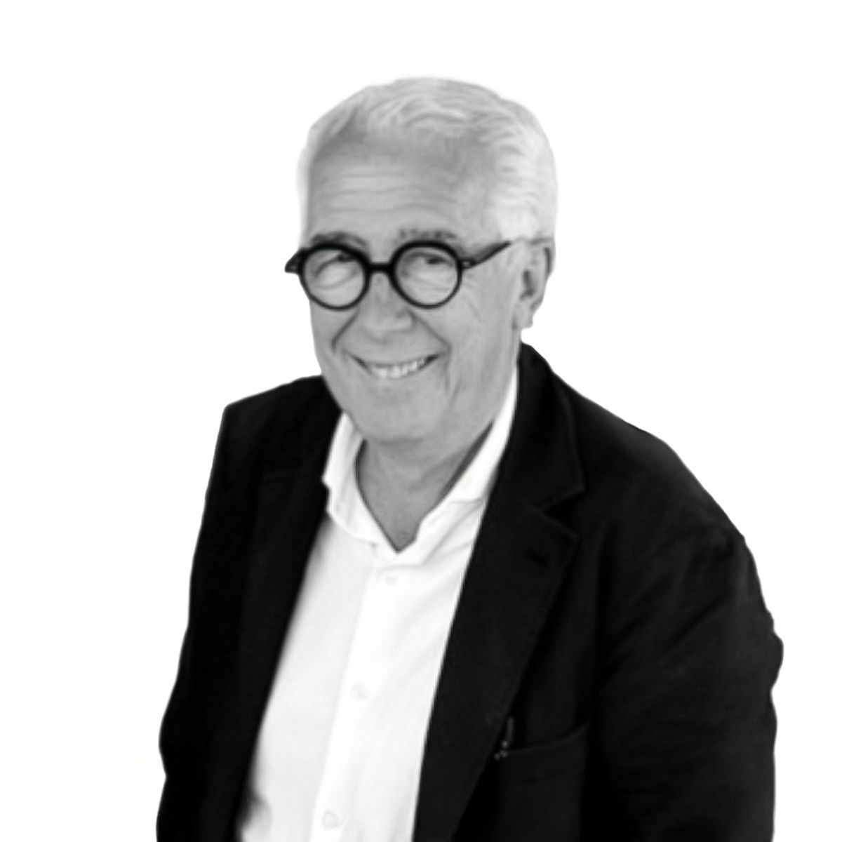 Uomo sorridente con gli occhiali, indossa una camicia bianca e una giacca nera su sfondo bianco.