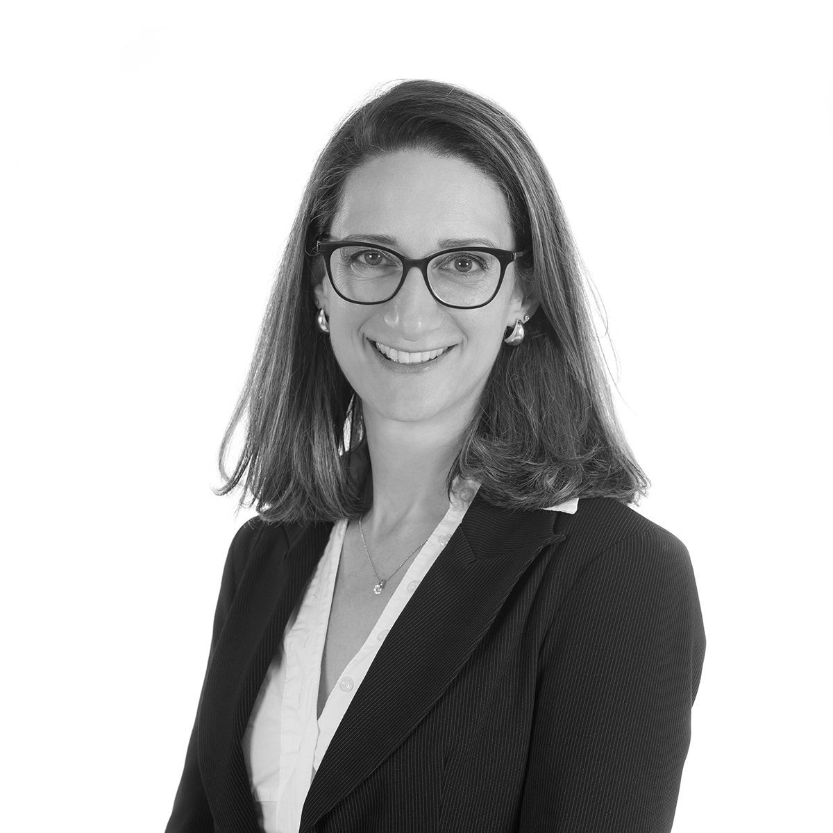 Donna con gli occhiali, sorridente, in giacca. Primo piano in bianco e nero.