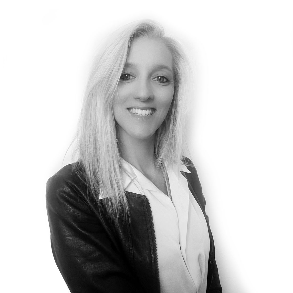 Donna con i capelli biondi che sorride indossando un blazer e una camicetta bianca.