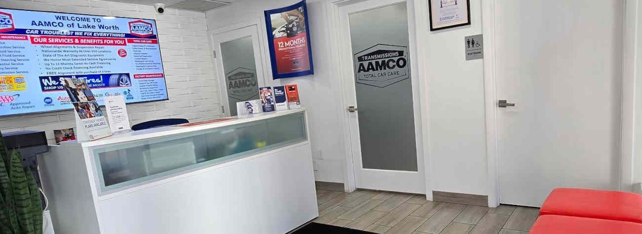 Reception area of an AAMCO Lake Worth, FL transmission and auto repair shop; includes desk, door with logo, promotional material.