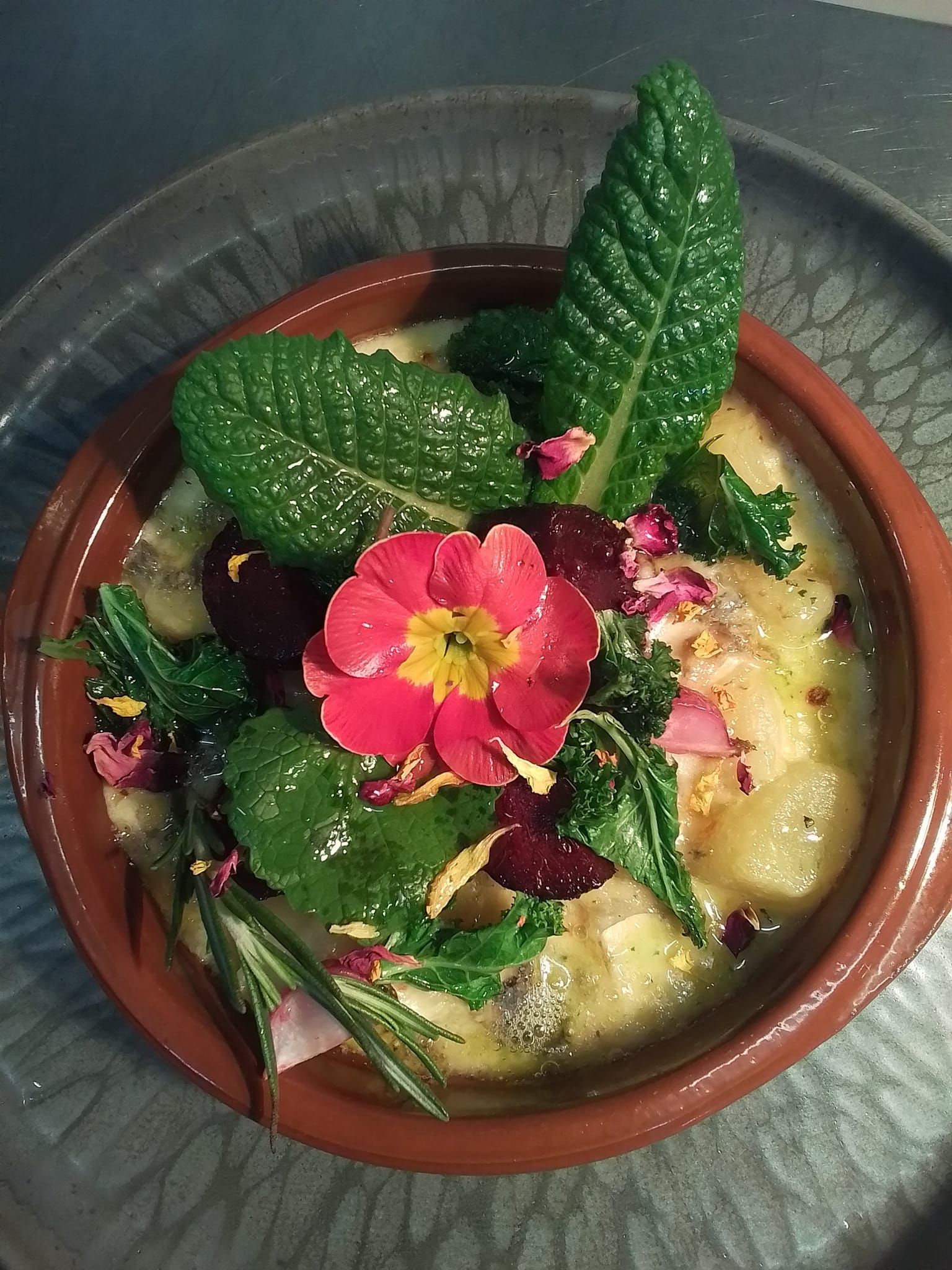 A bowl of food with a flower on top of it on a plate.