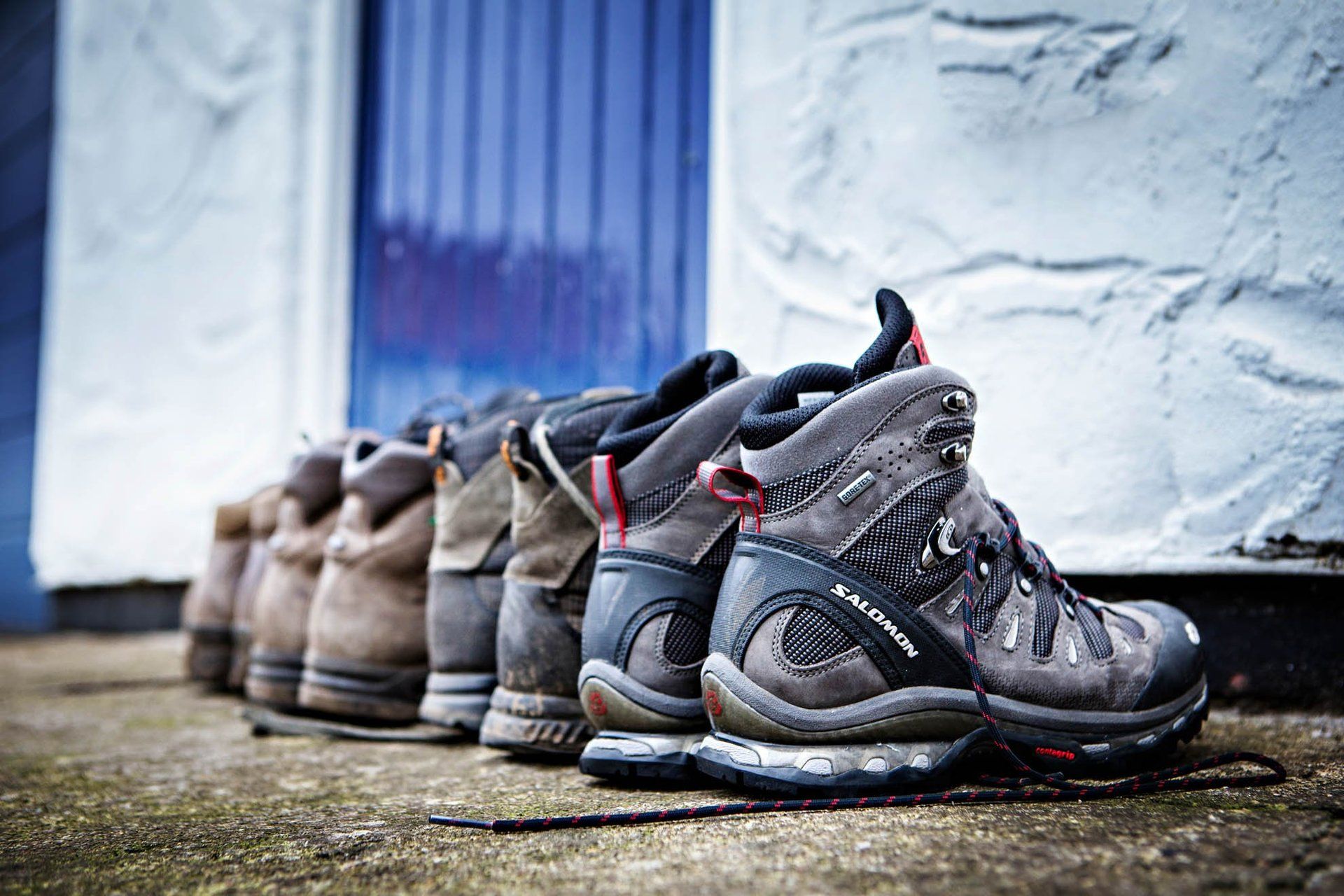 A row of hiking boots are lined up in front of a building.