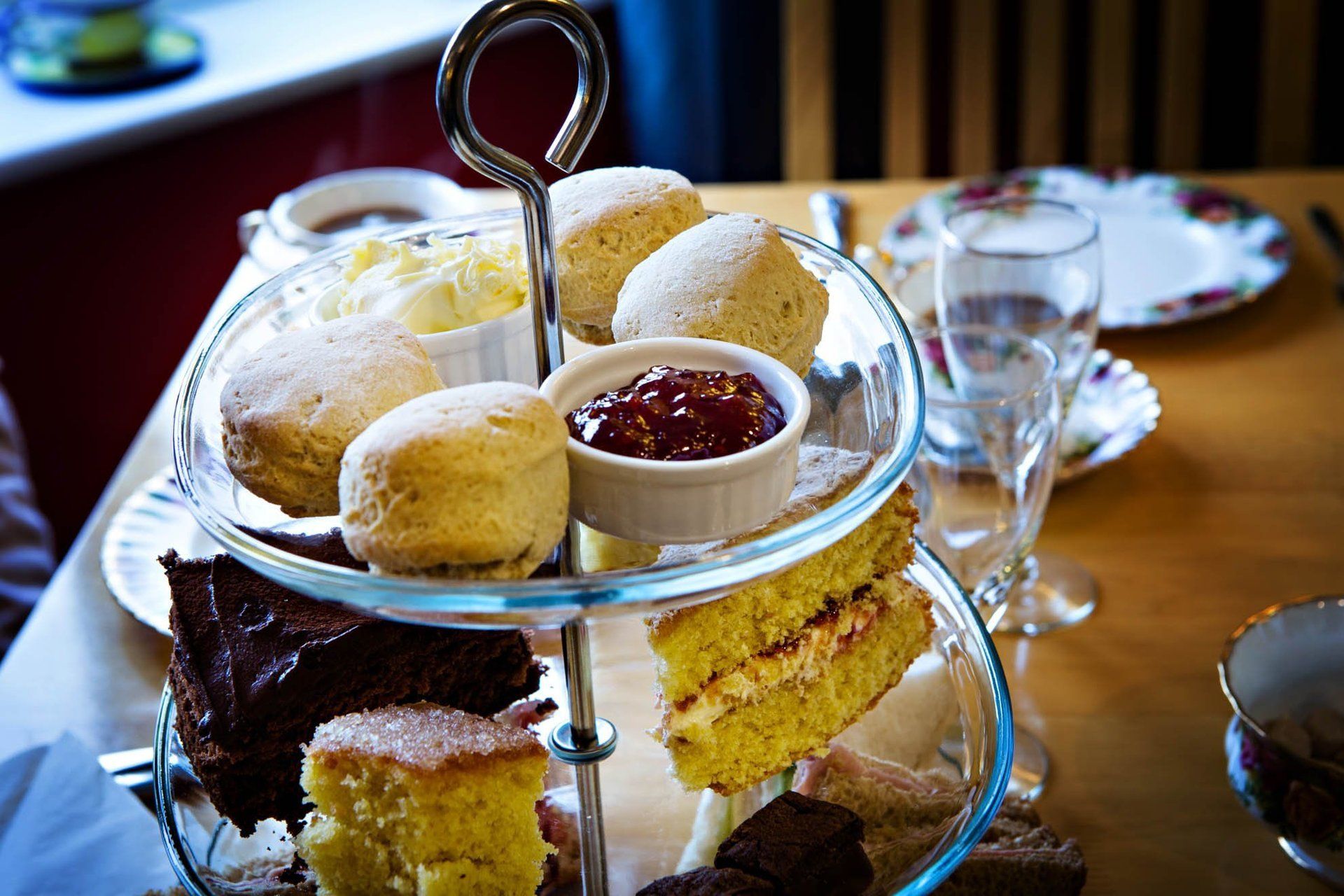 A glass tray filled with a variety of desserts on a table.
