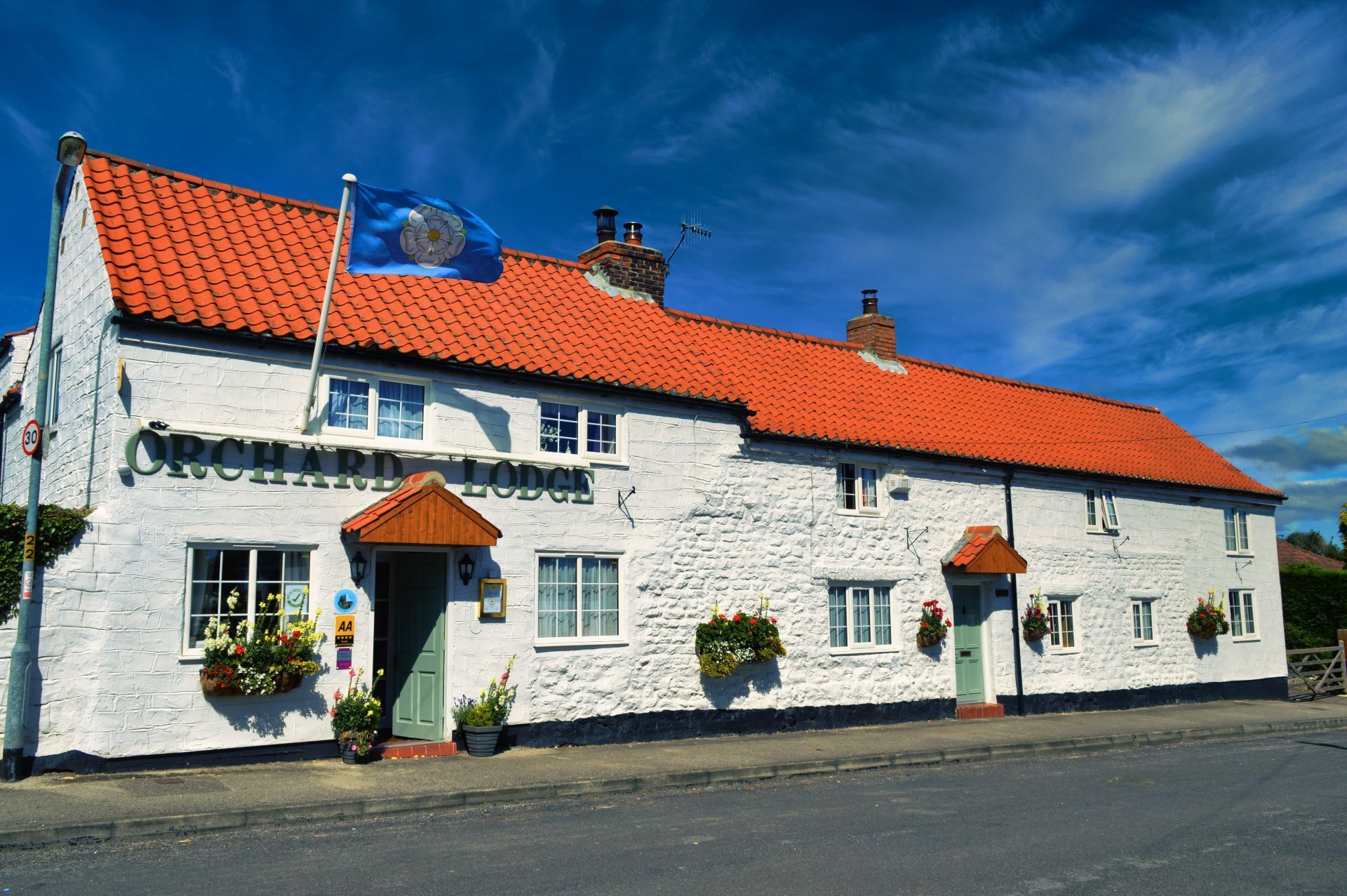 A white building with a red roof and a blue flag