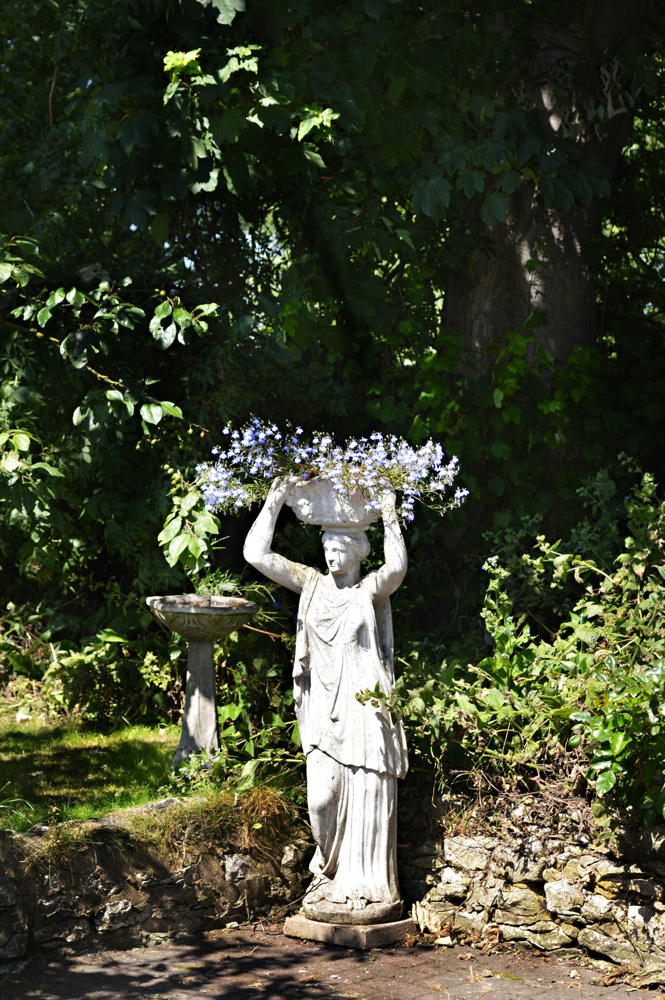 A statue of a woman holding a basket of flowers on her head.