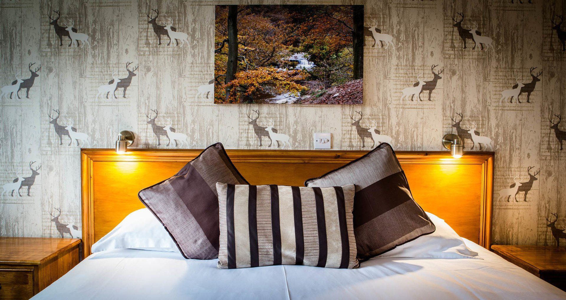 A bed with striped pillows and a picture on the wall above it.