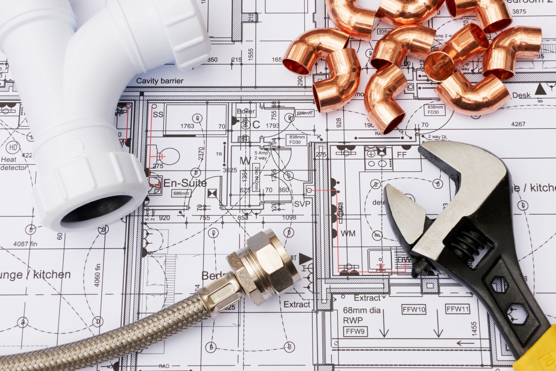 Plumbing tools and copper fittings arranged on a detailed building floor plan.