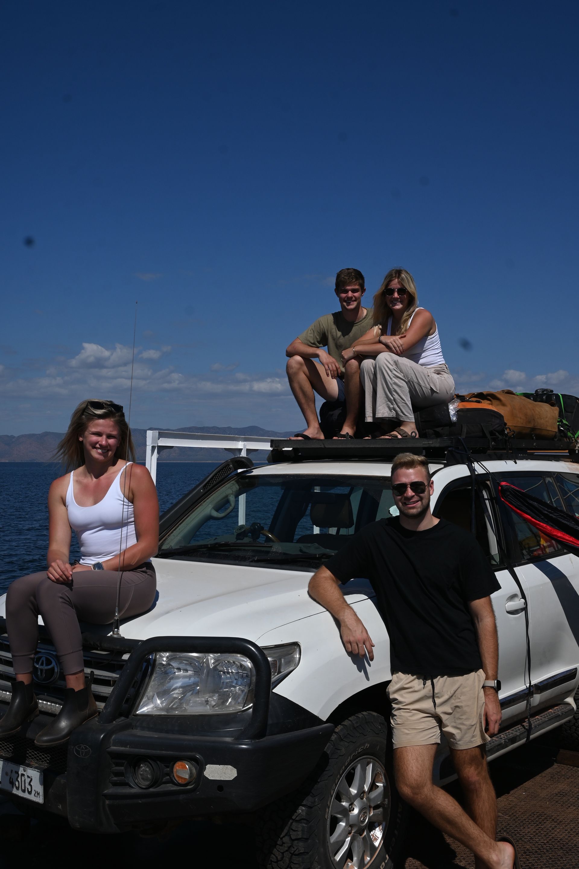 A group of people sitting on top of a white suv