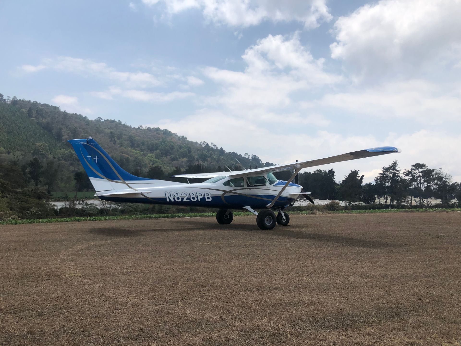 A small blue and white plane is parked on a dirt field