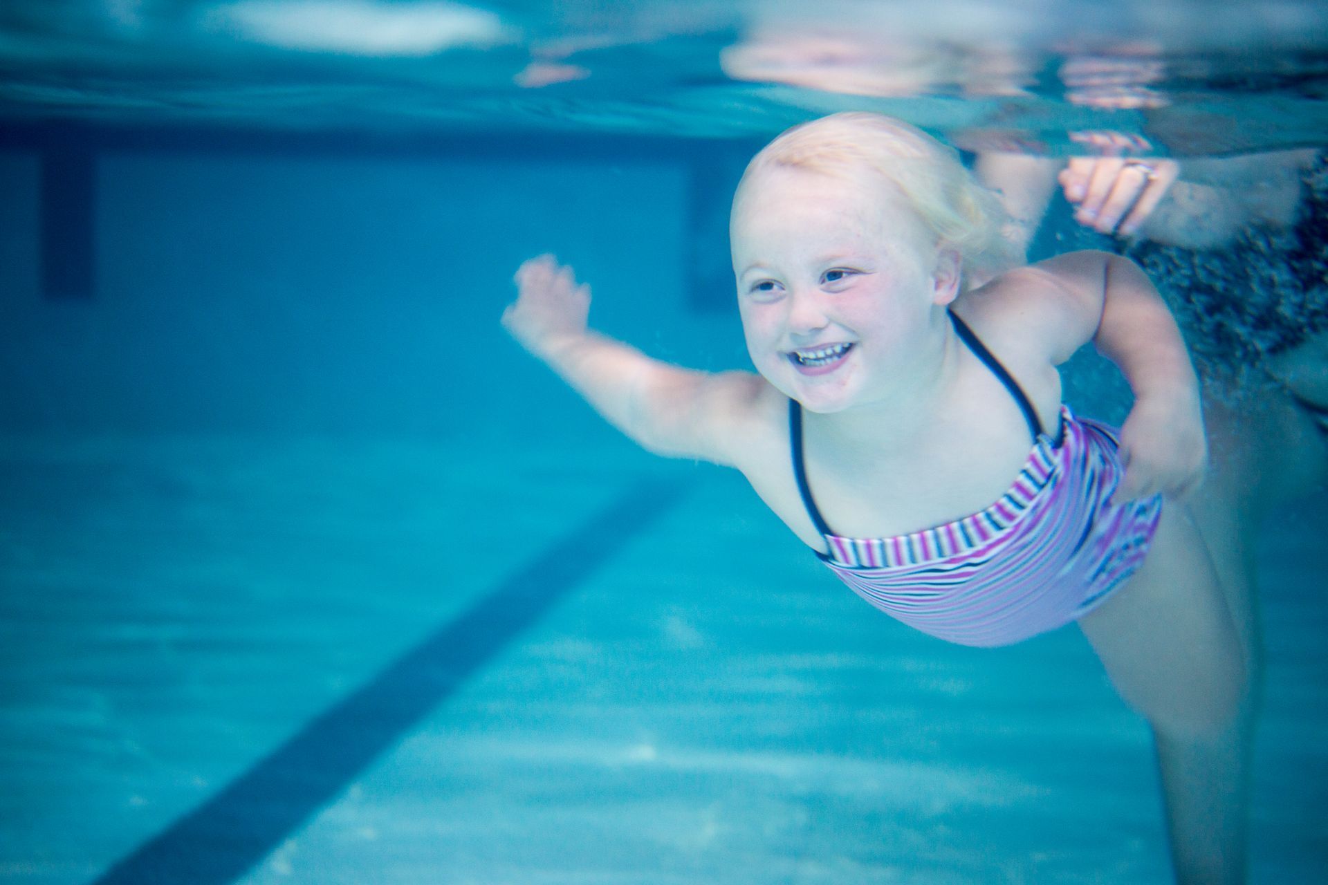 A little girl is swimming underwater in a swimming pool.