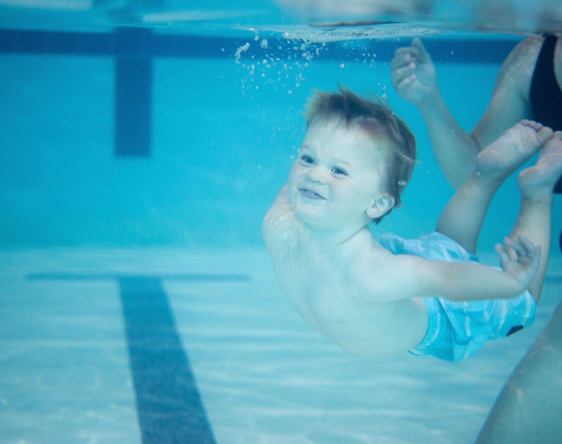 A little girl is swimming underwater in a swimming pool.