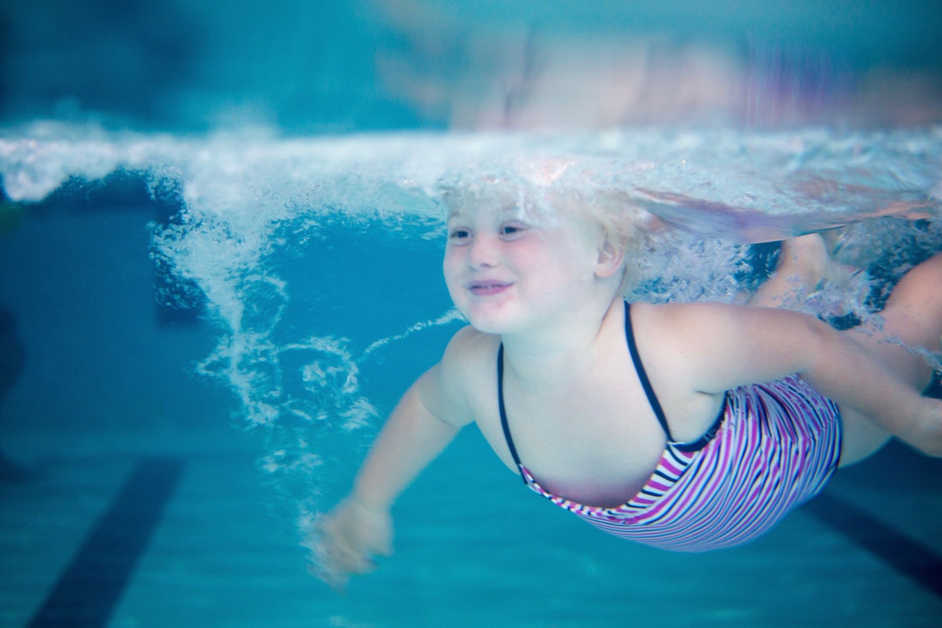 A woman is teaching a baby how to swim in a swimming pool.