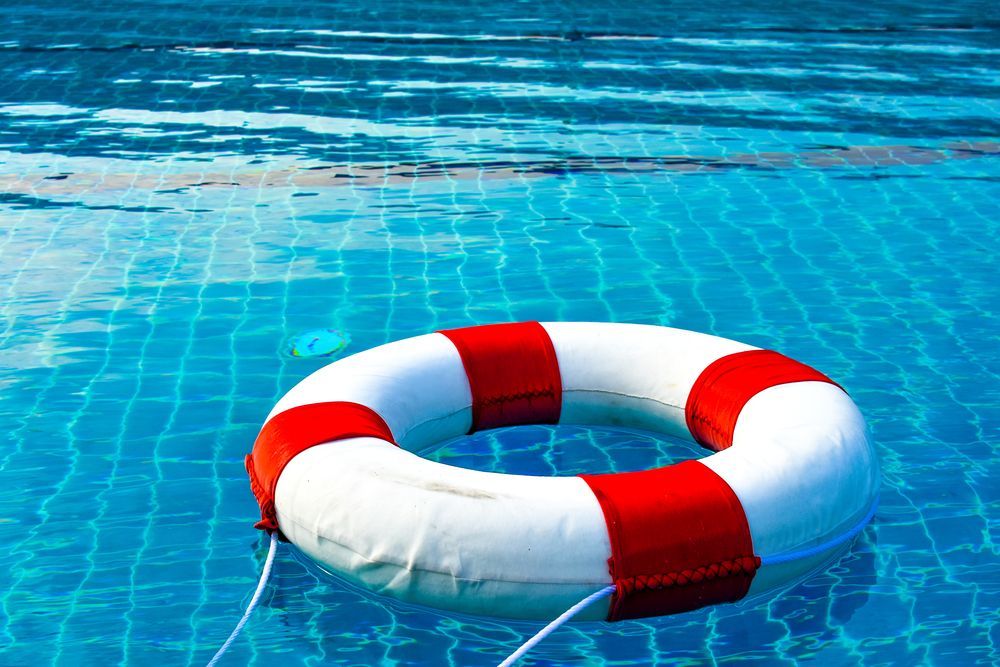 A red and white life preserver is floating in a swimming pool.