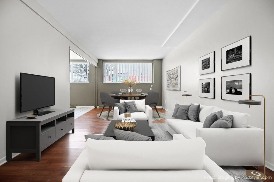Bright modern living room with white sofas, TV, coffee table, and wall art