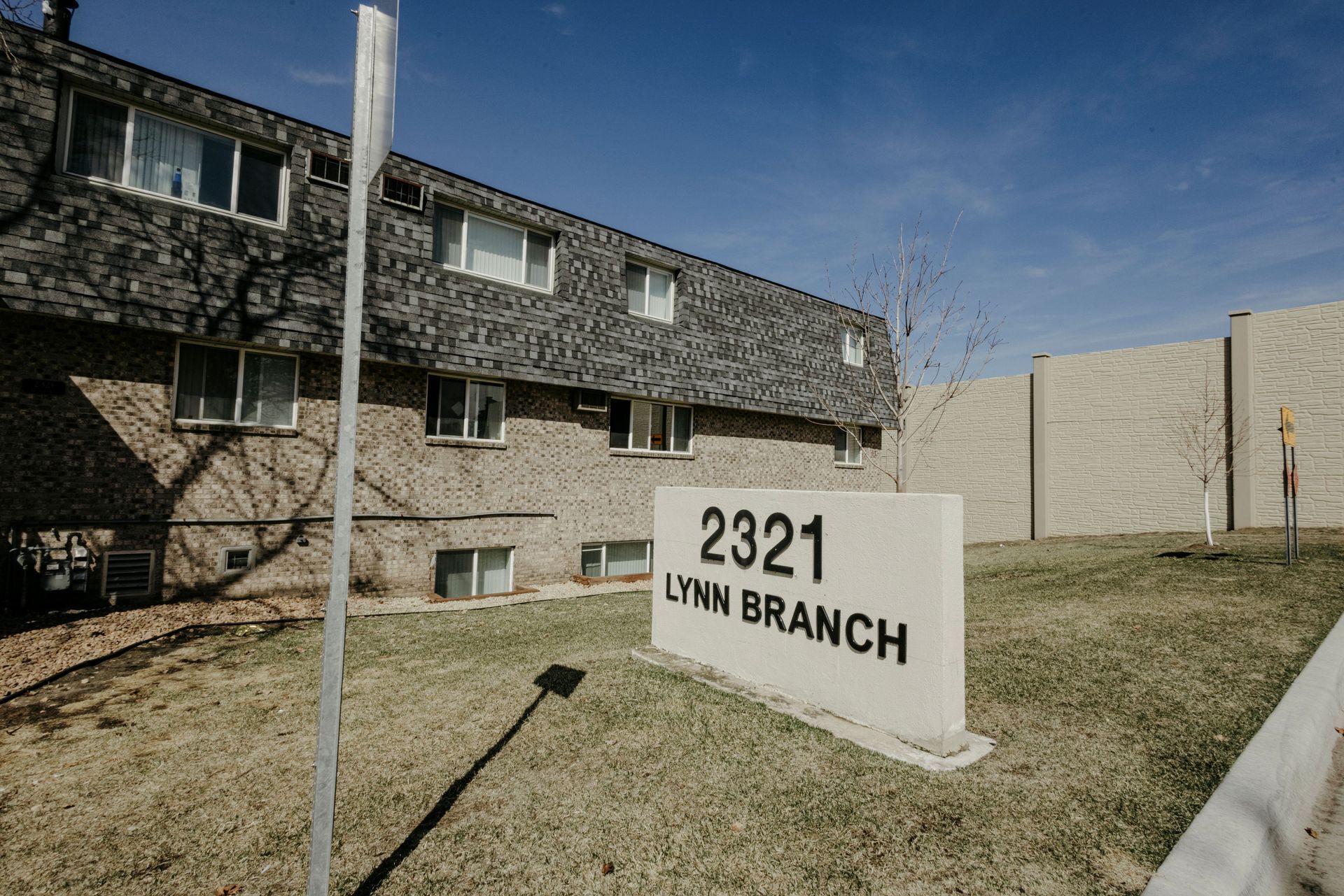Apartment building with sign reading “2321 Lynn Branch” in a grassy courtyard