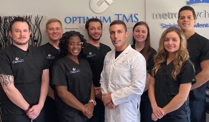 A group of people standing in front of a sign that says optimum tms
