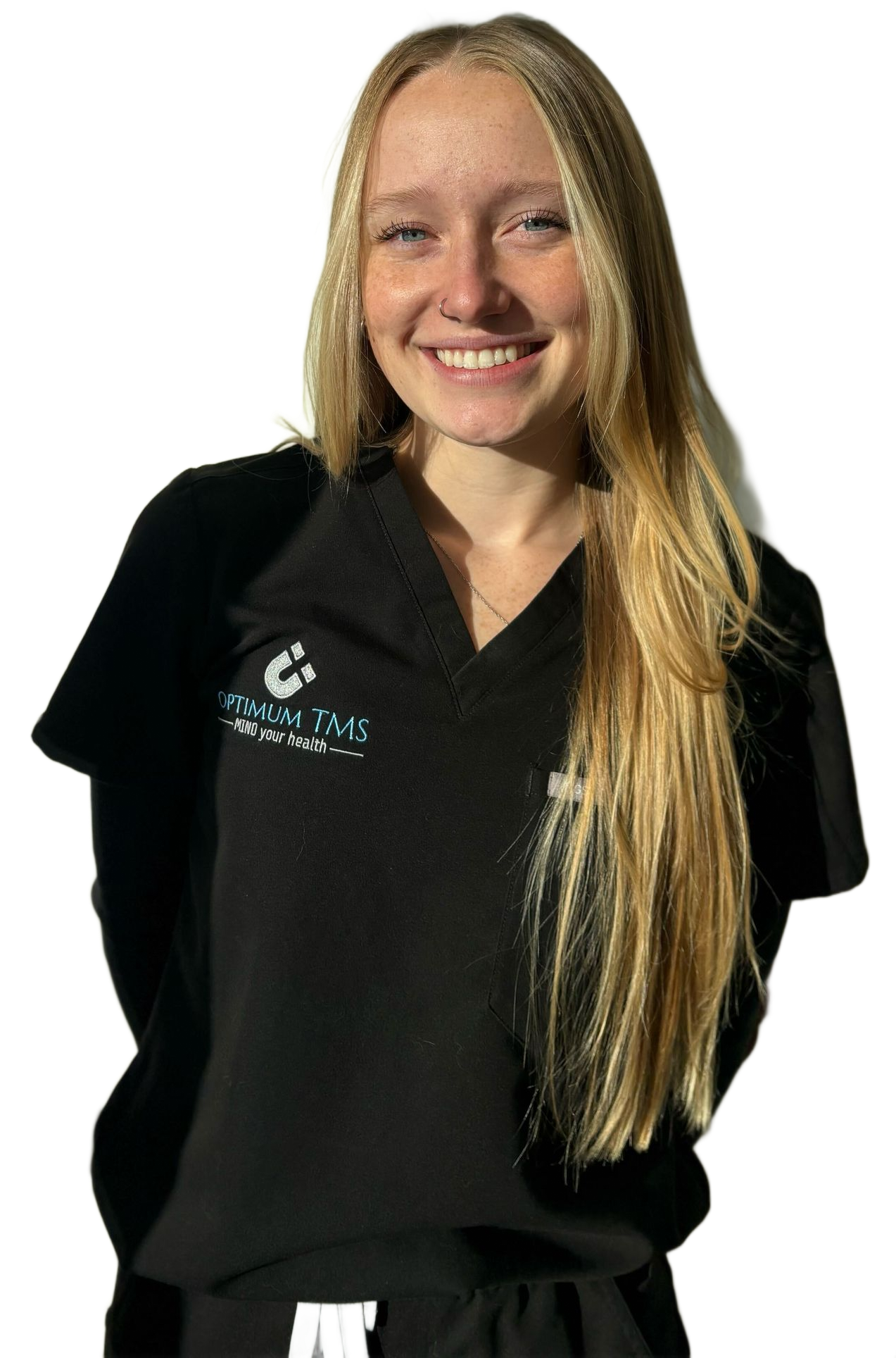 A woman with long blonde hair is wearing a black scrub and smiling.